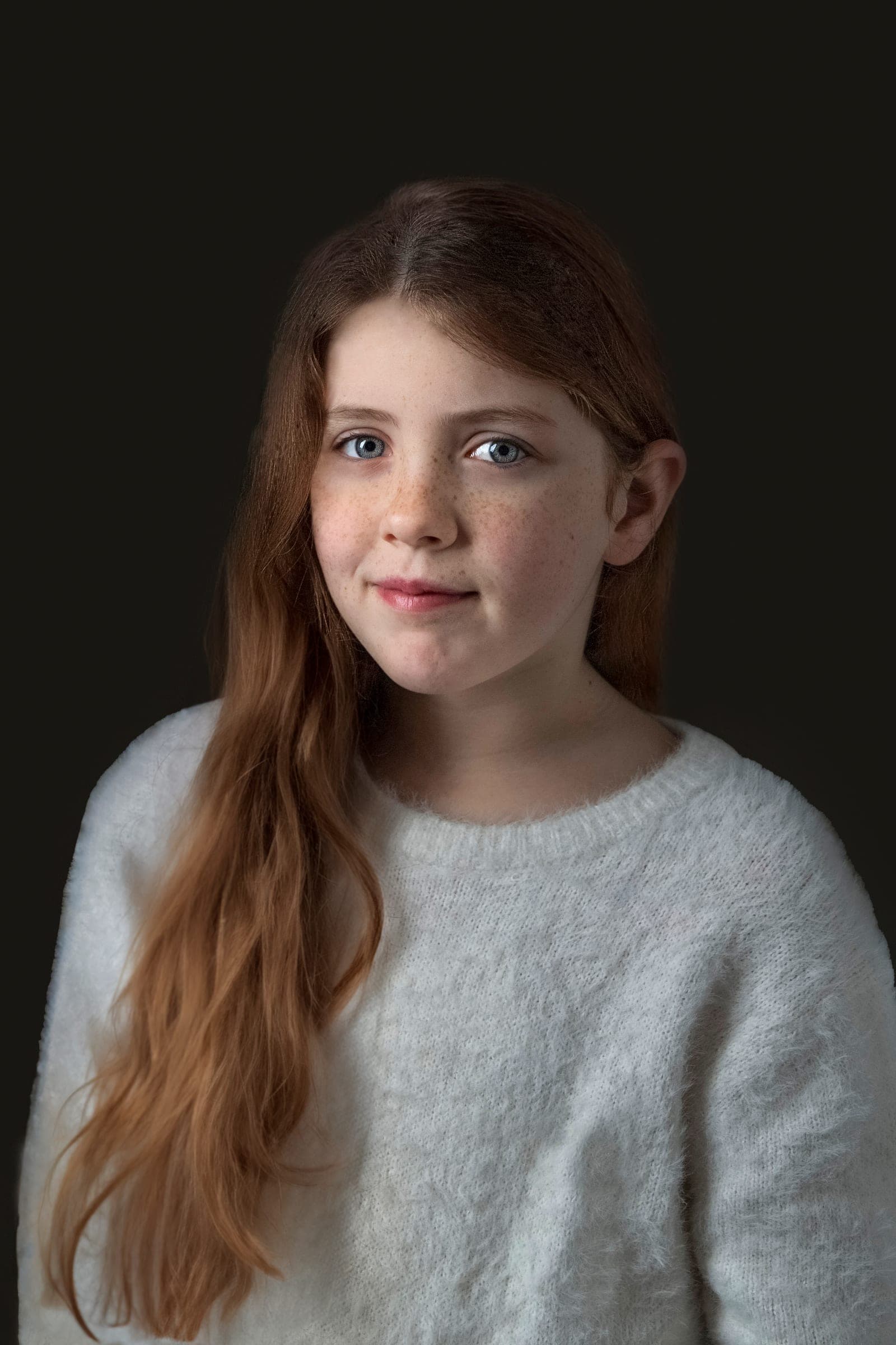 Fine art kinderportret met lang haar tegen een donkere achtergrond